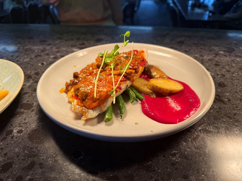 A chargrilled main course plated with vegetables and sauce